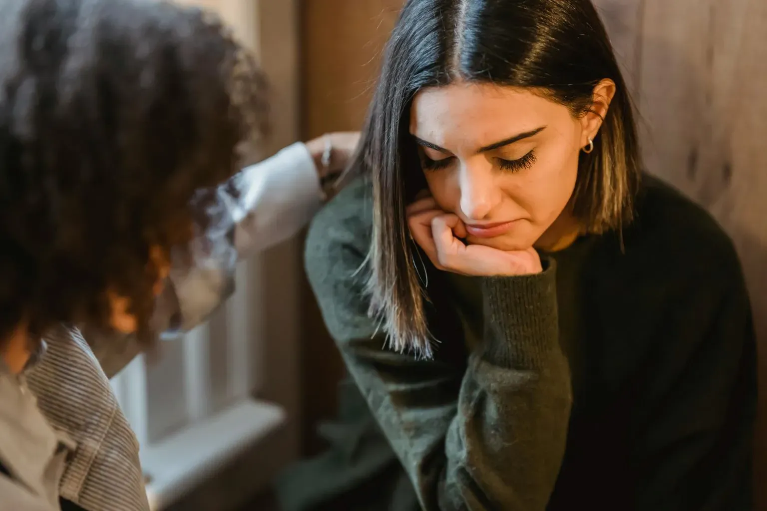 Woman comforting friend during her drug and alcohol intervention