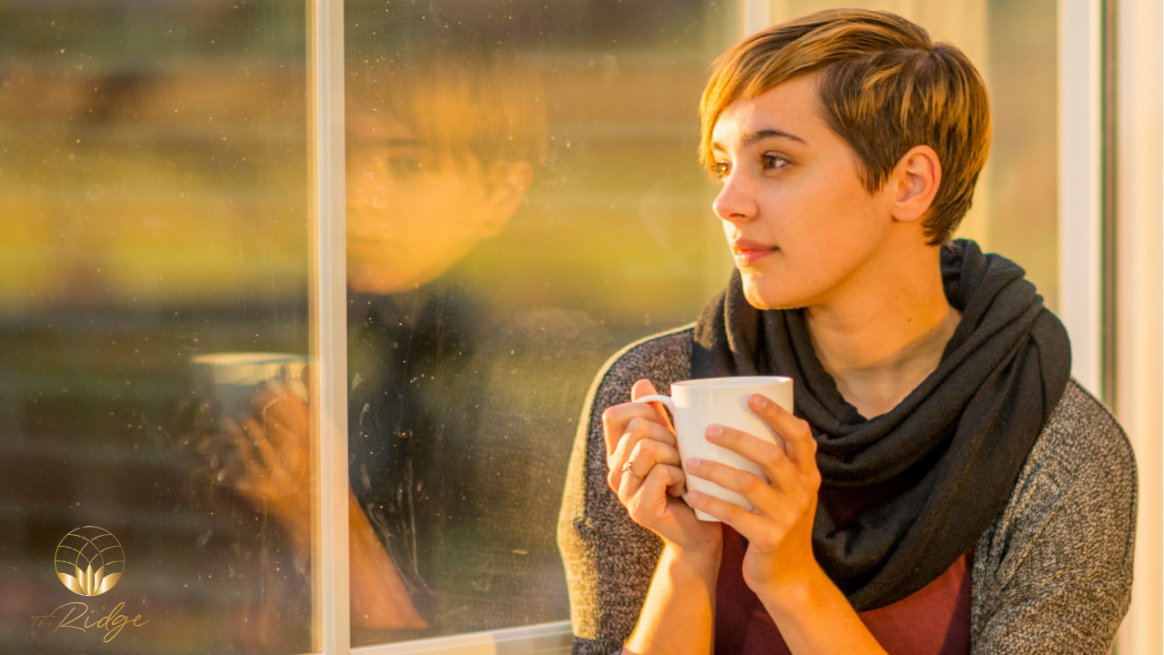 Woman drinking a hot beverage and looking out the window